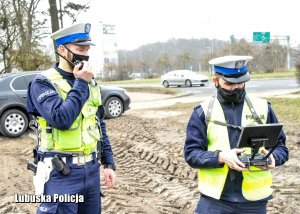 jeden policjant obsługuje drona, a drugi mówi do radiostacji