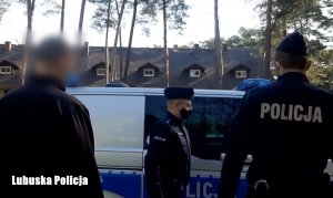 Mężczyzna, a w tle policjanci przy radiowozie.