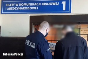 Policjant z mężczyzną przy kasie biletowej.