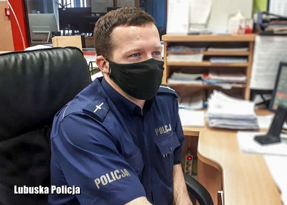 Umundurowany policjant w pomieszczeniu służbowym.