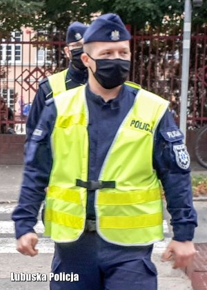 Umundurowany policjant w kamizelce odblaskowej.