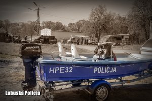 Policyjna łódź, a w tle policjanci i funkcjonariusze innych służb.