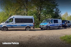 Policyjne radiowozy, a obok nich policjanci.