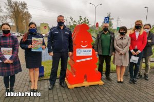 policjanci i urzędnicy stoją przy pojemniku na nakrętki