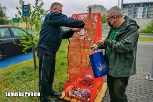 policjant i urzędnik wrzucają nakrętki do pojemnika