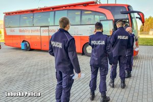 policjanci stoją w kolejce do krwiobusa