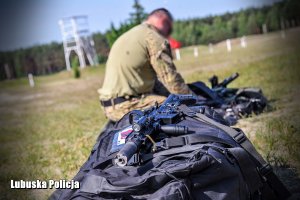 Karabinek na plecaku, a w tle policyjny kontrterrorysta.