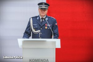 inspektor Jarosław Pasterski przemawia na tle flagi
