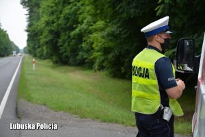 Policjant drogówki przy kontrolowanym pojeździe.