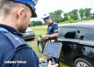 Policjanci drogówki podczas manewrowania dronem lotniczym.