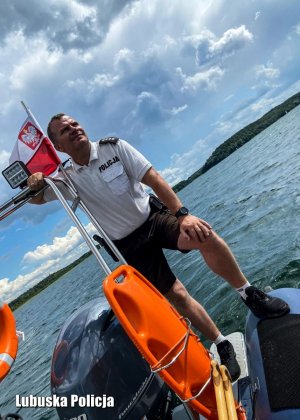 Policjant na łodzi motorowej, w tle jezioro.
