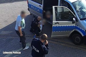 Policjanci udzielają pomocy dziecku przy radiowozie. Obok ojciec dziecka