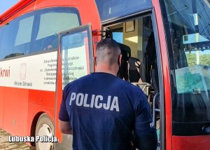 Policjant przed wejściem do krwiobusu.