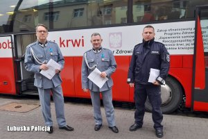 policjant wraz z zaproszonymi gośćmi przed krwiobusem