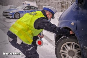 Policjant ruchu drogowego sprawdza stan opon