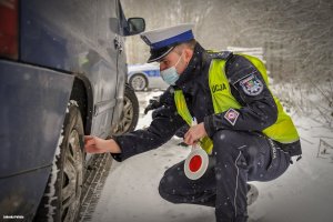 Policjant ruchu drogowego sprawdza stan opon