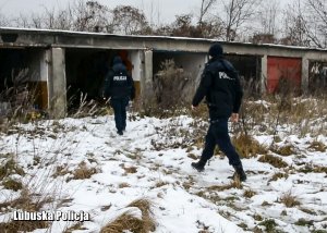 Policjanci idą w kierunku opuszczonych garaży, w których mogą przebywać osoby bezdomne.