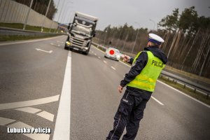 Policjant zatrzymuje ciężarówkę do kontroli drogowej.