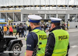 Policjanci drogówki na tle stadionu żużlowego.