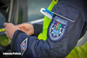 Policyjna naszywka na ramieniu policjanta, który przeprowadza kontrolę drogową.