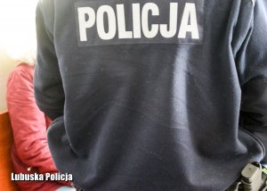 policjant i siedząca osoba w tle