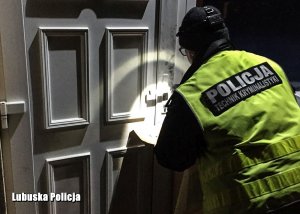 Policyjny technik kryminalistyki przeprowadza oględziny drzwi wejściowych