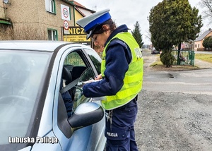 Policjantka drogówki podczas przeprowadzania kontroli drogowej.