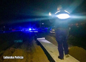Policjant świecący latarką w mroku