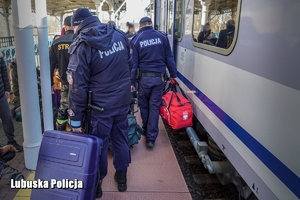 policjanci niosą walizki na peronie