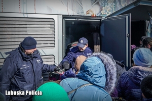 Policjanci pomagają wejść do pociągu rodzinie uchodźców.