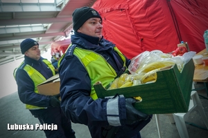 Policjanci niosący skrzynki z owocami.