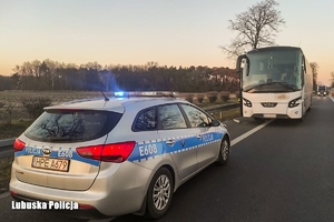 Radiowóz z sygnałami błyskowymi oraz zatrzymany autobus