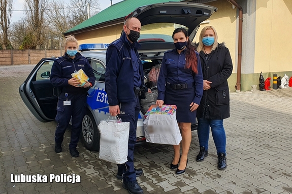 Policjanci oraz pracownicy przy radiowozie z darami