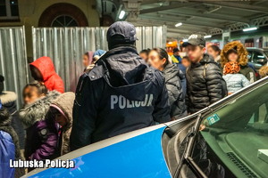 policjant obserwuje osoby idące na stacji kolejowej