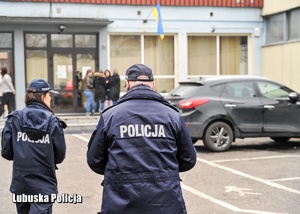 Policjanci idący w kierunku ośrodku, w którym znajdują się uchodźcy z Ukrainy.