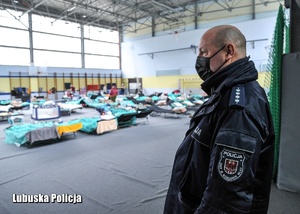 Policjant na sali, w której znajdują się uchodźcy z Ukrainy.