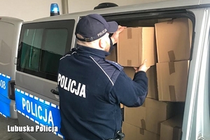 policjant wypakowuje zabezpieczone papierowy z radiowozu