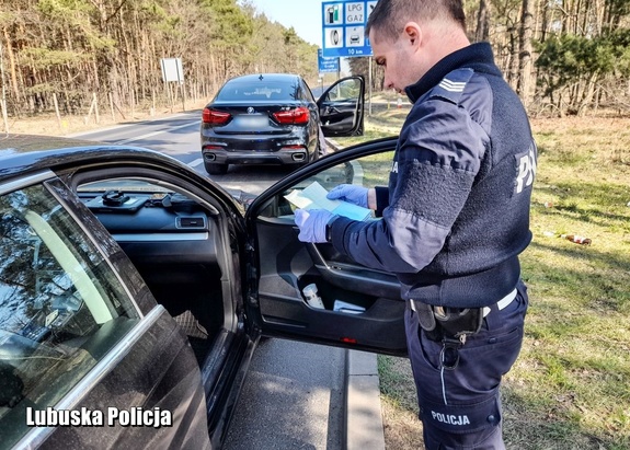 Policjant sprawdza dokumentację przy radiowozie