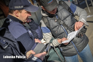 Policjant z mężczyzną na peronie kolejowym.