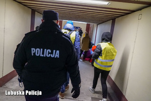 Policjant przechodzi pod peronem w towarzystwie uchodźców