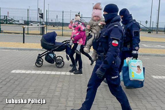 Policjant niosący dziecko na przejściu granicznym.