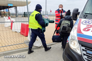 Policjant niesie dziecko ma rękach do karetki pogotowia