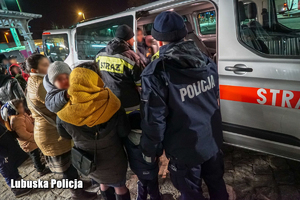 Policjant, strażak i uchodźcy przy busie.