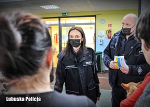 Policjantka i policjant przeprowadzają rozmowę z grupą uchodźców