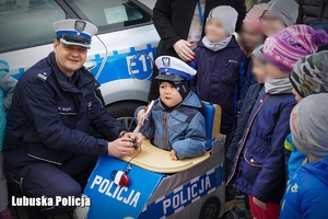 Chłopiec wraz z policjantem na tle radiowozu
