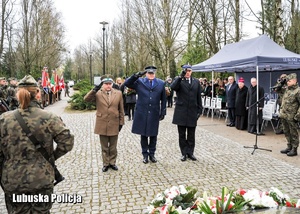 Przedstawiciele służb mundurowych składają hołd przed pomnikiem.