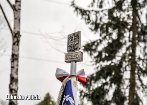 Szczyt sztandaru z napisem Policja i godłem.