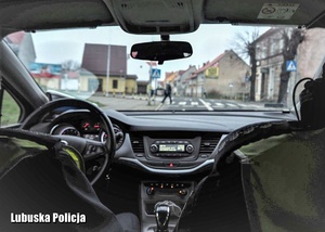 Policjanci w radiowozie obserwują ruch na przejściu dla pieszych