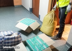 policjant pakuje zabezpieczone papierosy i tytoń do kartonów