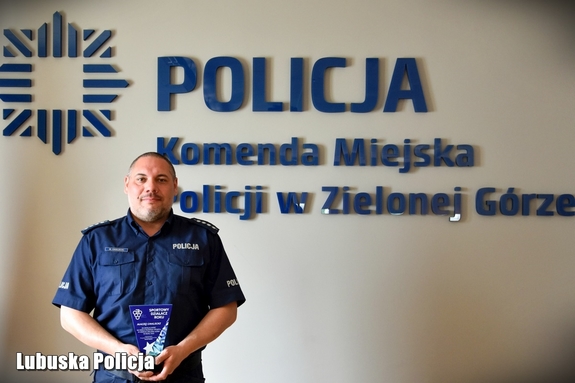 Policjant na tle logo zielonogórskiej komendy